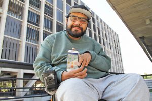 Pedro Aguilera mostrando la aplicación en un celular. 
